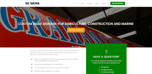 Website homepage for BC Signs showcasing custom signage for agriculture, construction, and marine sectors. Features a prominent red sign with the word 'GRAND' and options for services and contact information.