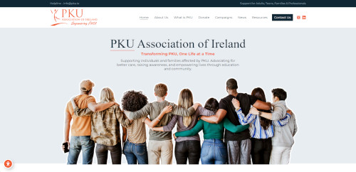 A group of diverse individuals standing closely together, arms around each other's shoulders, in front of a light background with the text 'PKU Association of Ireland' at the top. The atmosphere conveys a sense of community and support.